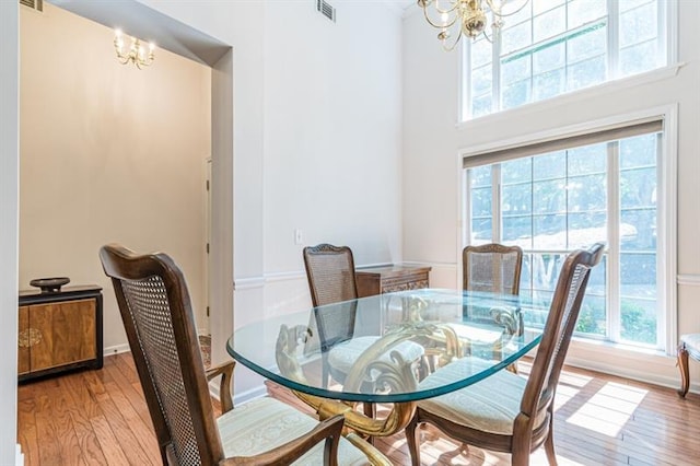 dining space with a towering ceiling, light hardwood / wood-style floors, and a chandelier