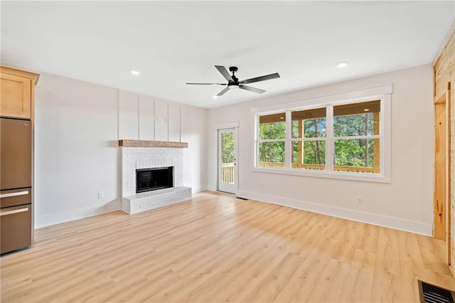 unfurnished living room featuring ceiling fan, light hardwood / wood-style floors, and a fireplace