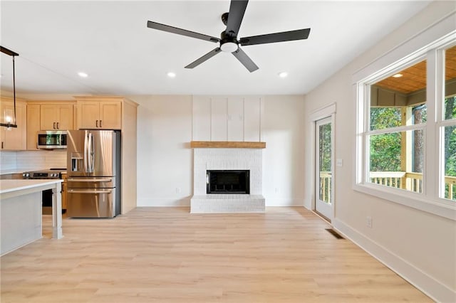 unfurnished living room featuring ceiling fan, a fireplace, and light wood-type flooring