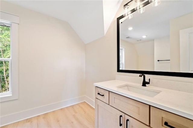 bathroom featuring hardwood / wood-style floors, vaulted ceiling, vanity, and a healthy amount of sunlight