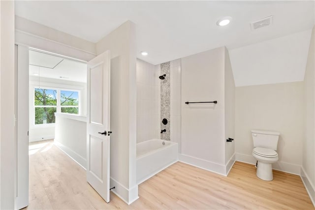 bathroom featuring hardwood / wood-style flooring, toilet, and tiled shower / bath