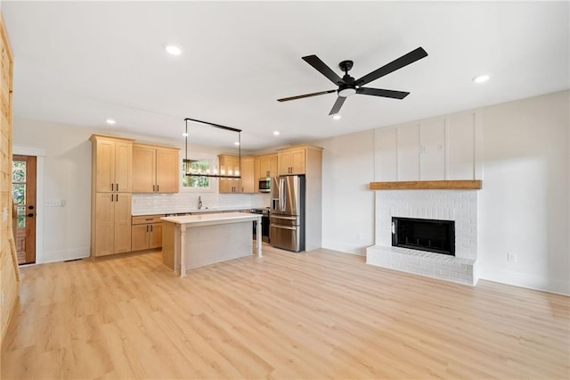 kitchen with appliances with stainless steel finishes, a center island, decorative light fixtures, light hardwood / wood-style floors, and ceiling fan