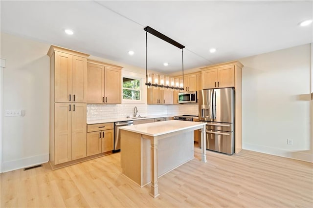 kitchen with appliances with stainless steel finishes, light hardwood / wood-style flooring, light brown cabinets, and hanging light fixtures