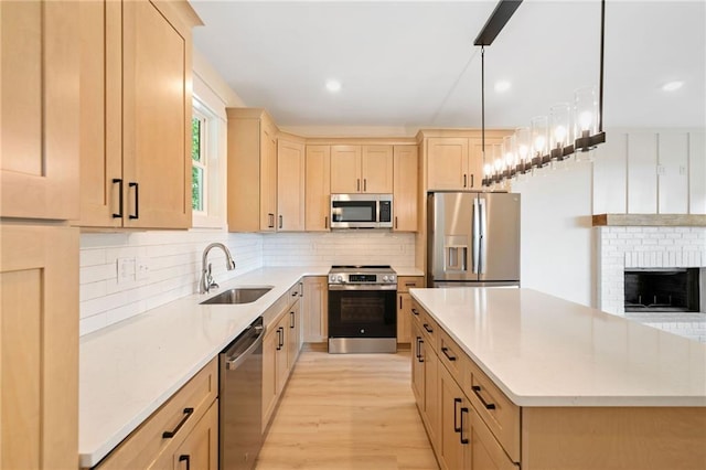 kitchen featuring decorative light fixtures, light brown cabinets, stainless steel appliances, light hardwood / wood-style floors, and sink