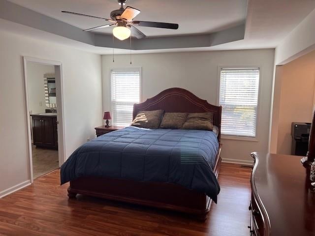 bedroom featuring ensuite bath, dark wood-type flooring, multiple windows, and ceiling fan