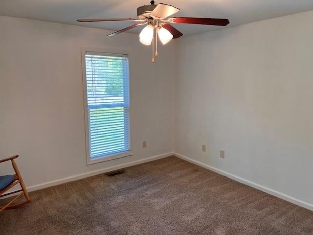 carpeted spare room with ceiling fan