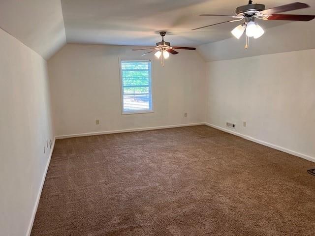 additional living space with lofted ceiling, dark carpet, and ceiling fan