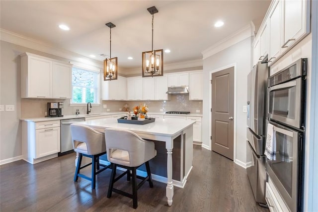 kitchen featuring a kitchen bar, stainless steel appliances, white cabinets, and a kitchen island