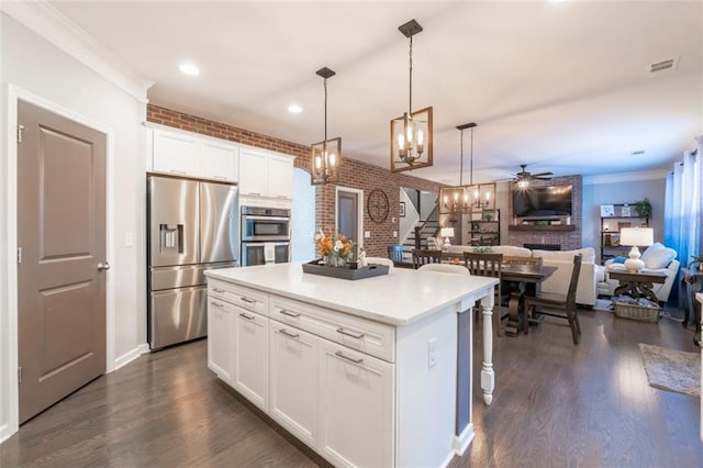 kitchen with decorative light fixtures, white cabinetry, a center island, stainless steel appliances, and crown molding