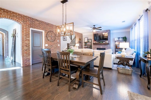 dining space featuring ceiling fan, brick wall, dark hardwood / wood-style flooring, and a brick fireplace