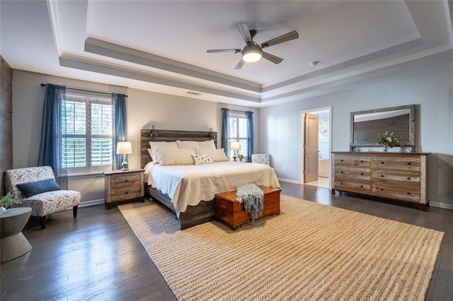 bedroom with multiple windows, ensuite bath, a raised ceiling, and ceiling fan