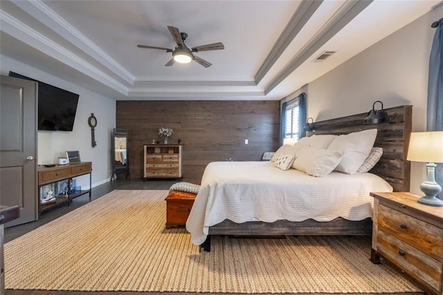 bedroom featuring a raised ceiling, ceiling fan, ornamental molding, and wooden walls