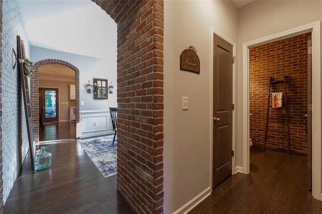 hallway featuring brick wall and dark hardwood / wood-style floors