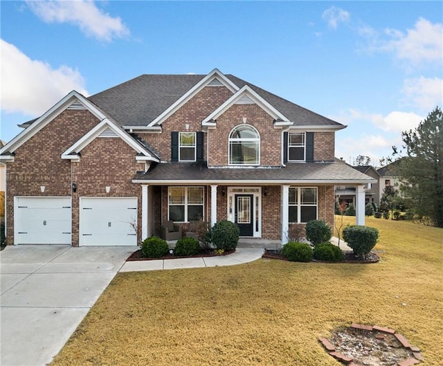 view of front of house featuring a front yard, a porch, and a garage