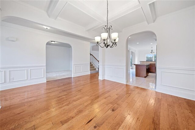 unfurnished dining area featuring light hardwood / wood-style floors, crown molding, beam ceiling, and an inviting chandelier