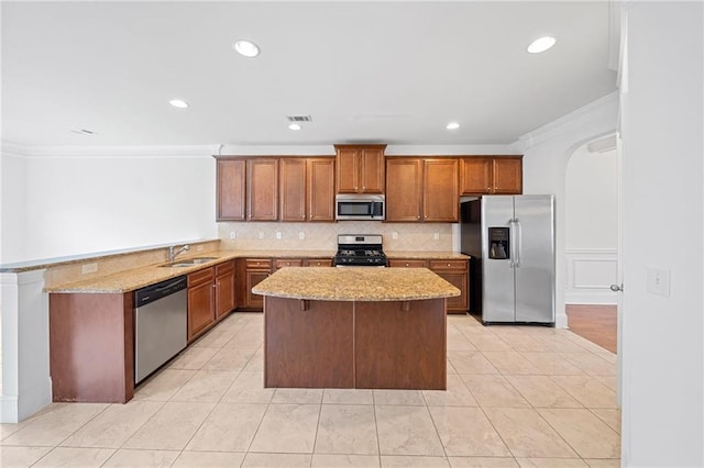 kitchen with kitchen peninsula, sink, stainless steel appliances, and ornamental molding