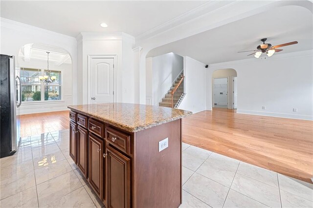 kitchen featuring ceiling fan with notable chandelier, crown molding, light hardwood / wood-style flooring, a kitchen island, and stainless steel refrigerator