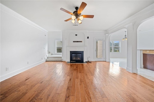 unfurnished living room featuring ceiling fan, ornamental molding, and light hardwood / wood-style flooring