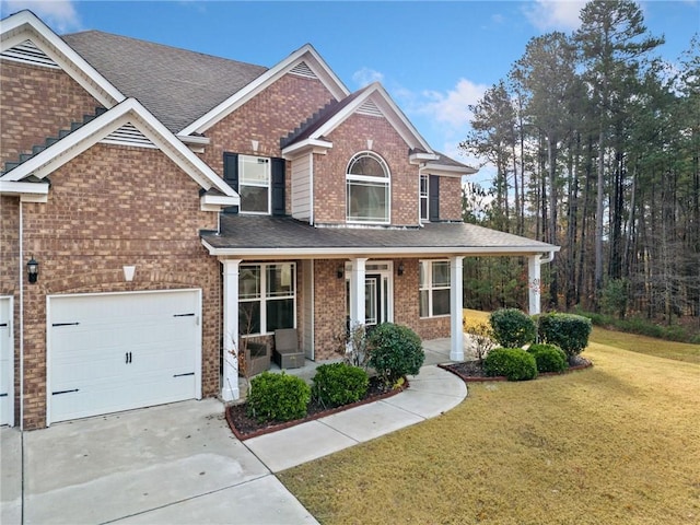 view of front of property featuring a porch, a garage, and a front yard