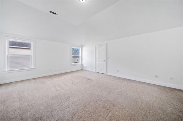 carpeted empty room with lofted ceiling