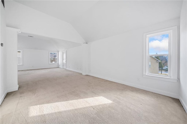 spare room featuring light colored carpet and vaulted ceiling