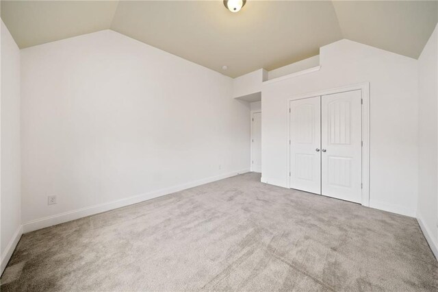 unfurnished bedroom with carpet, a closet, and vaulted ceiling