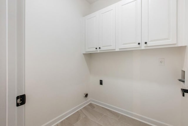 clothes washing area featuring hookup for an electric dryer, light tile patterned floors, and cabinets