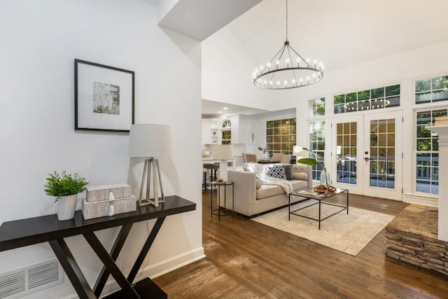 living room with an inviting chandelier, french doors, dark hardwood / wood-style floors, and a high ceiling