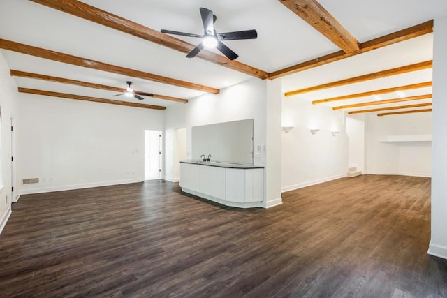 unfurnished living room featuring dark wood-type flooring, ceiling fan, and beamed ceiling