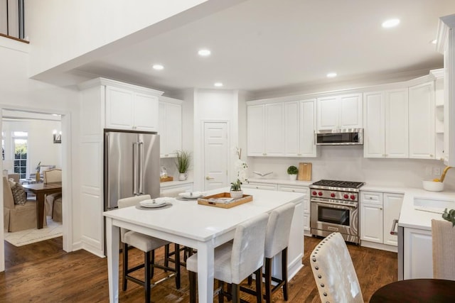 kitchen with high end appliances, white cabinets, and dark hardwood / wood-style flooring