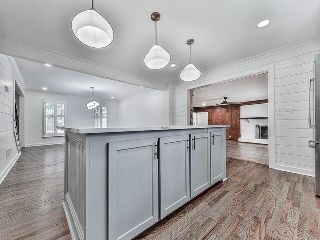 kitchen with dark wood-type flooring, crown molding, decorative light fixtures, gray cabinets, and a kitchen island