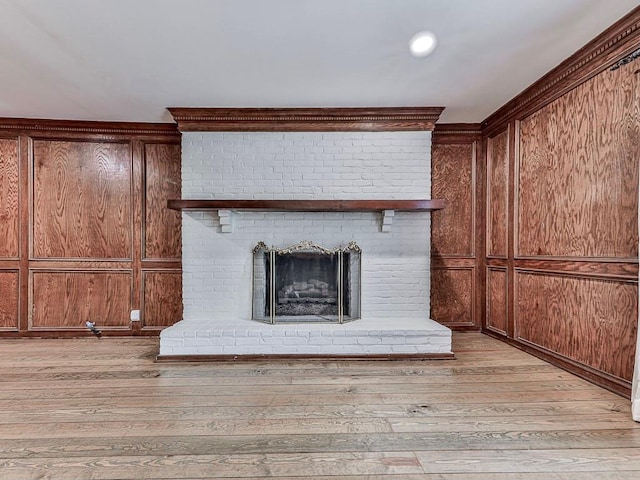 interior details featuring wood walls, hardwood / wood-style floors, and a brick fireplace