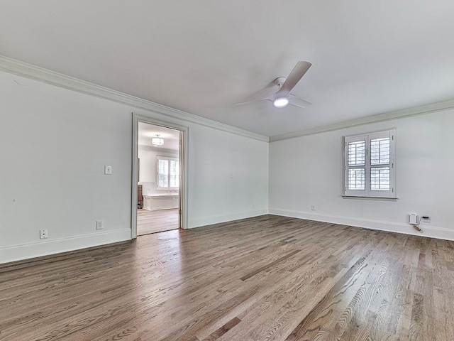 empty room with hardwood / wood-style floors, crown molding, and a wealth of natural light