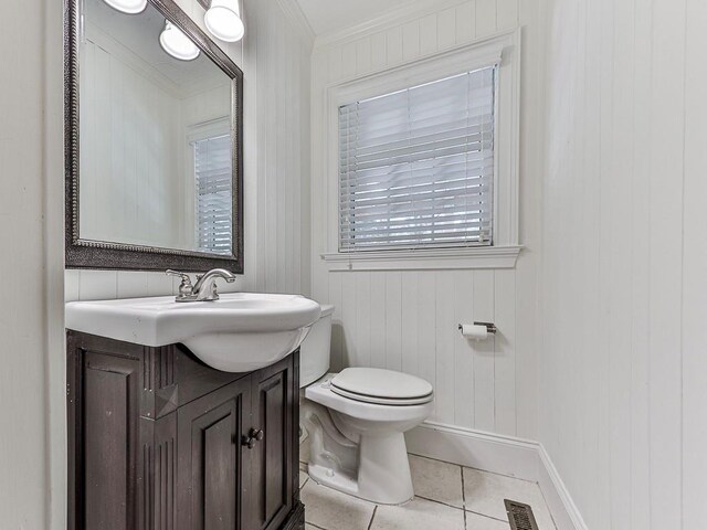 bathroom with tile patterned flooring, wood walls, toilet, vanity, and ornamental molding