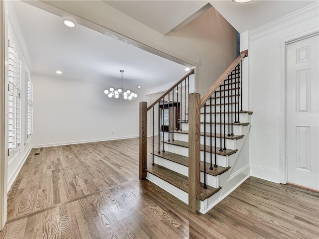 stairway featuring hardwood / wood-style floors, an inviting chandelier, and ornamental molding