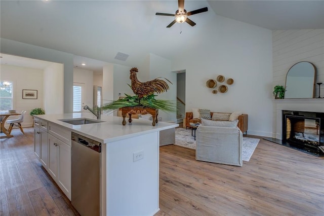 kitchen featuring light wood-style flooring, a sink, open floor plan, light countertops, and stainless steel dishwasher