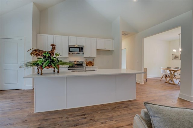 kitchen with light wood-type flooring, white cabinetry, stainless steel appliances, and light countertops