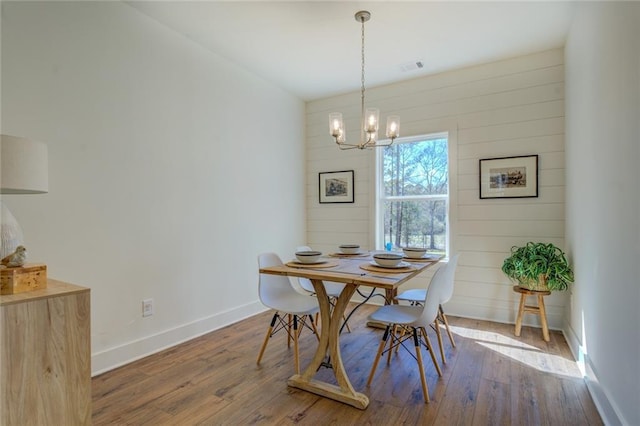 dining room featuring wood-type flooring, visible vents, baseboards, and a notable chandelier