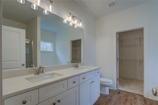 bathroom featuring toilet, double vanity, a sink, and wood finished floors