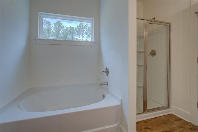 bathroom with wood finished floors, a shower stall, and a bath