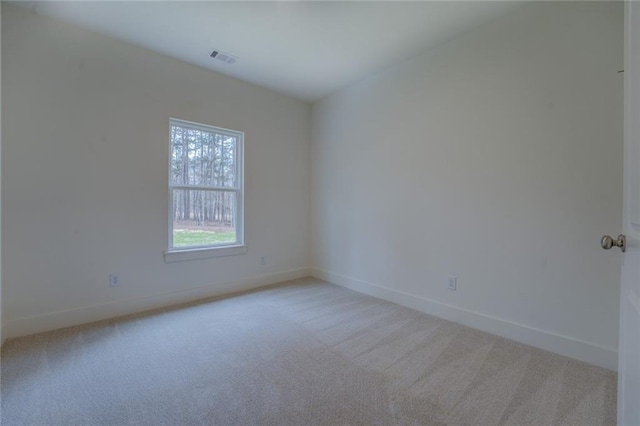 empty room with carpet flooring, visible vents, and baseboards