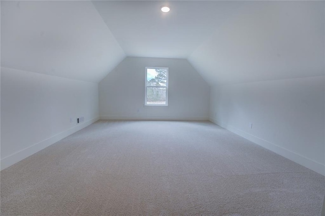 bonus room with lofted ceiling, light carpet, and baseboards