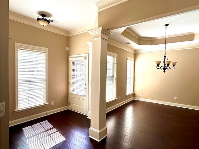 interior space featuring a tray ceiling, ornamental molding, dark hardwood / wood-style flooring, ceiling fan with notable chandelier, and ornate columns