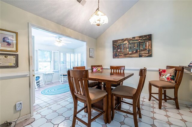 tiled dining room with ceiling fan with notable chandelier and lofted ceiling