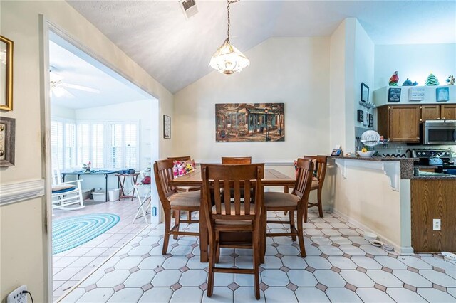 dining room with ceiling fan with notable chandelier and vaulted ceiling