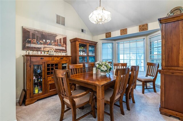 dining room featuring lofted ceiling, light carpet, and a chandelier