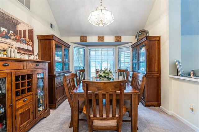 carpeted dining area with lofted ceiling and a chandelier