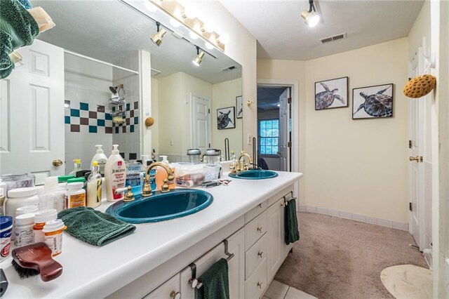 bathroom featuring tiled shower, vanity, and tile patterned flooring