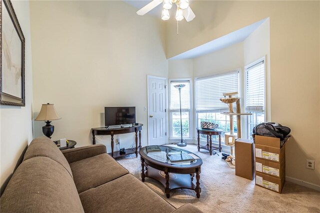 carpeted living room featuring a towering ceiling and ceiling fan