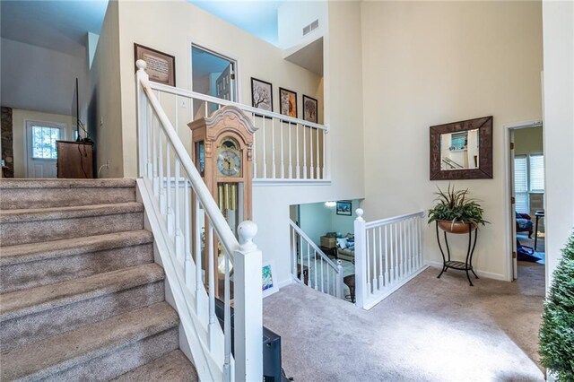 staircase with carpet floors and a towering ceiling